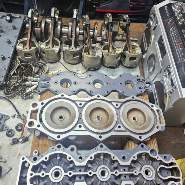 Engine block, cylinder head and pistons disassembled and laid out for measurement and rebuilding